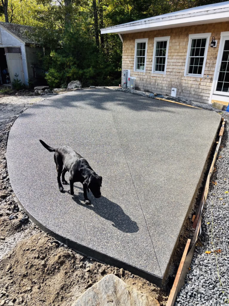Exposed aggregate concrete patio with a dog walking across it