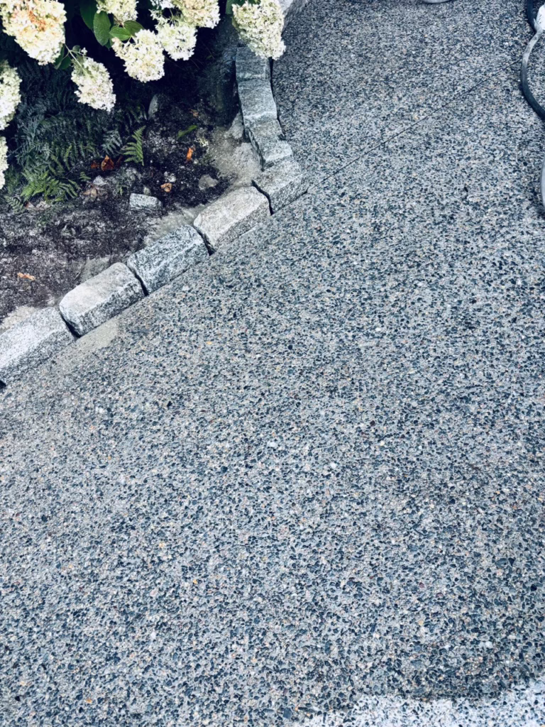 Close-up of an exposed aggregate concrete finish along a stone border